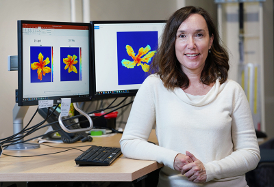 Photo of Lori Hoagland with computer screens showing hyperspectral images of plants in the bakground.